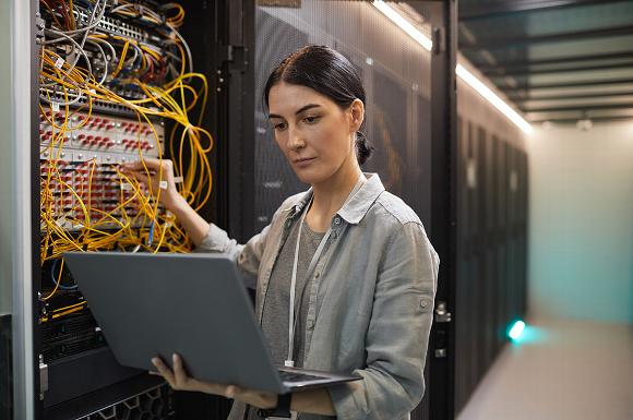Woman holding laptop and performing audit on data centre