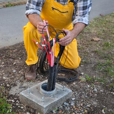 Man organising underground network cables through pipe